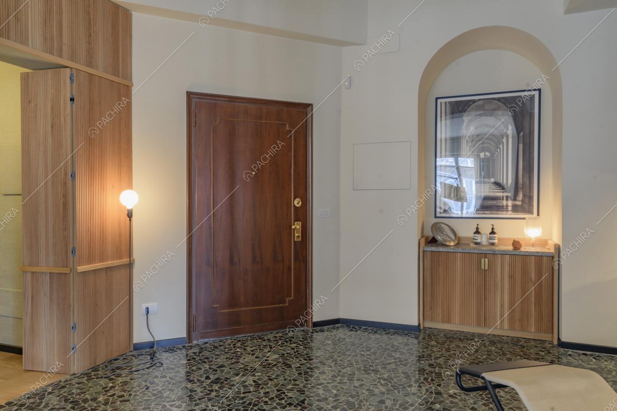 Atrio con pavimento in marmo, pareti bianche e vista sulla porta d'ingresso in legno