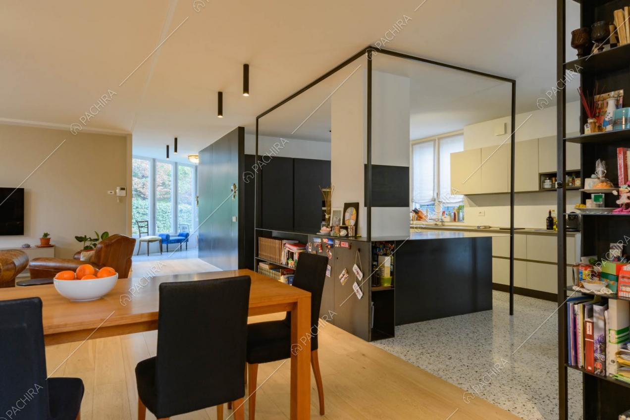 Cucina nera a parete e tavolo da pranzo in legno nel grande open space