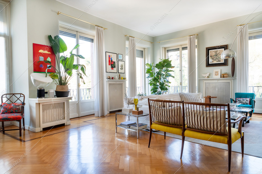 Salotto con pavimento in parquet a spina di pesce e porte-finestre per accedere al balcone