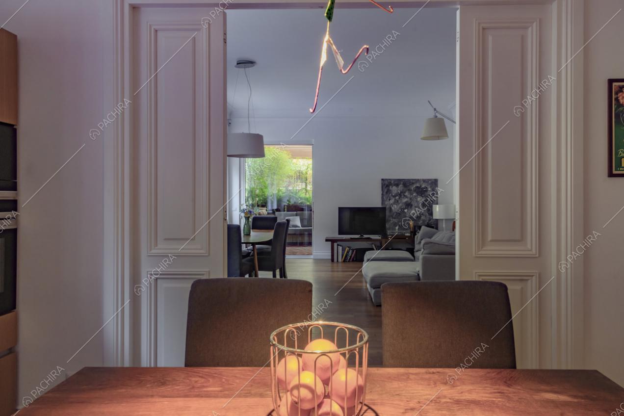 Dal tavolo da pranzo in legno della cucina vista sulla sala separata dalle porte bianche con boiserie