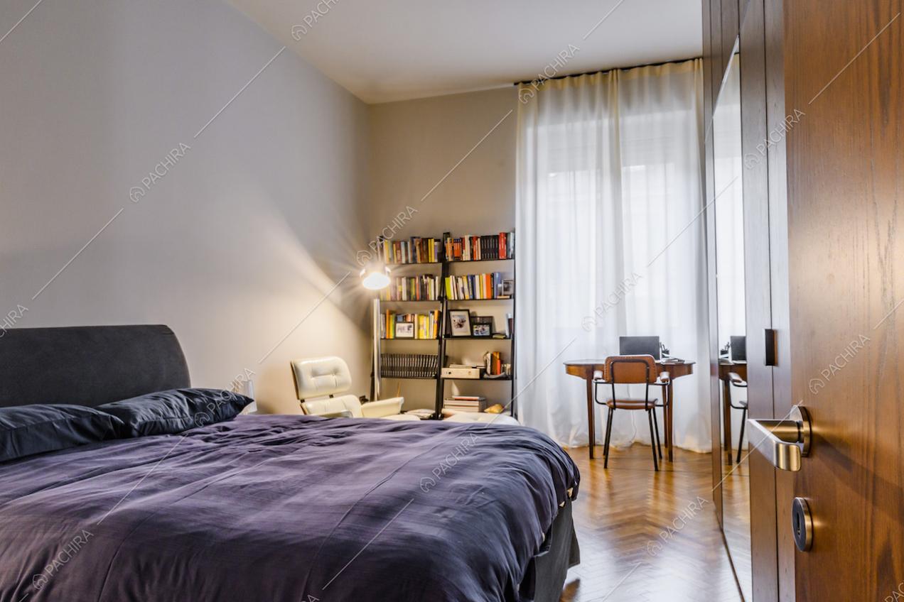 Camera da letto padronale con ampia finestra e tende bianche