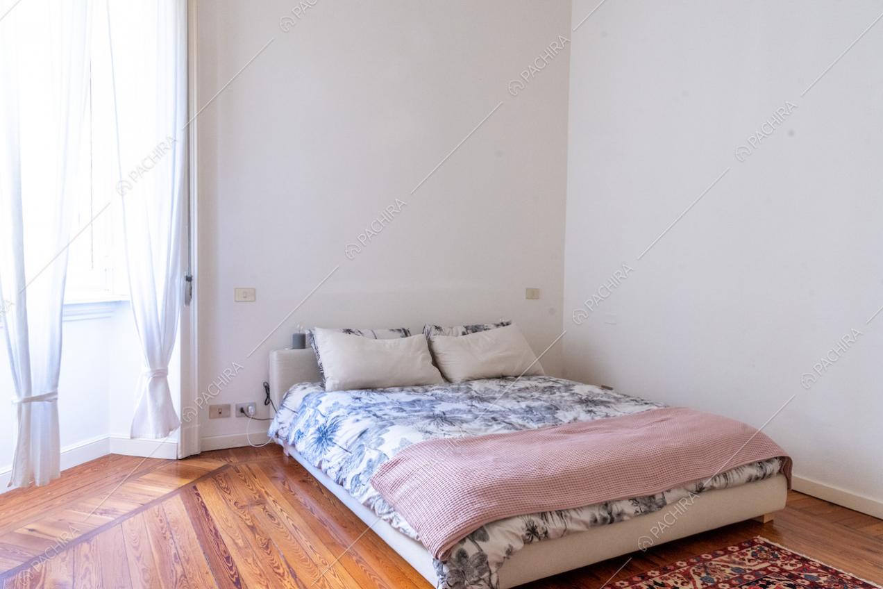 Letto matrimoniale in una luminosa camera da letto con pavimento in parquet a listoni