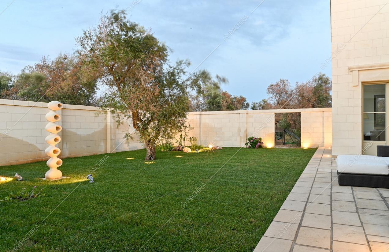 Giardino curatissimo con ulivo, circondato da mura in pietra bianche