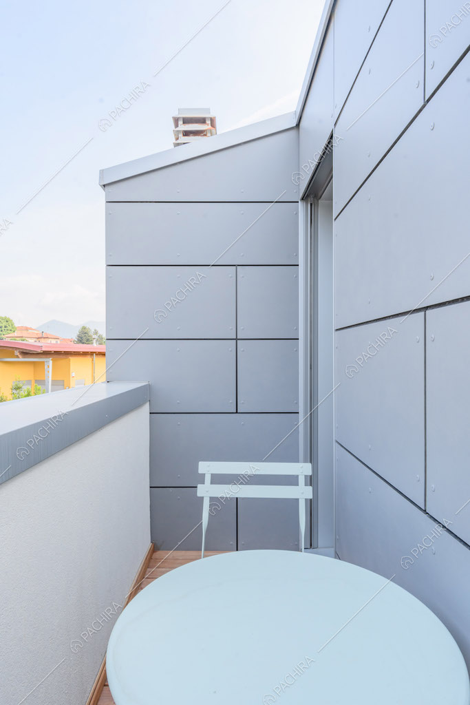 Tavolo e sedia bianchi sul balcone con vista sugli esterni grigi