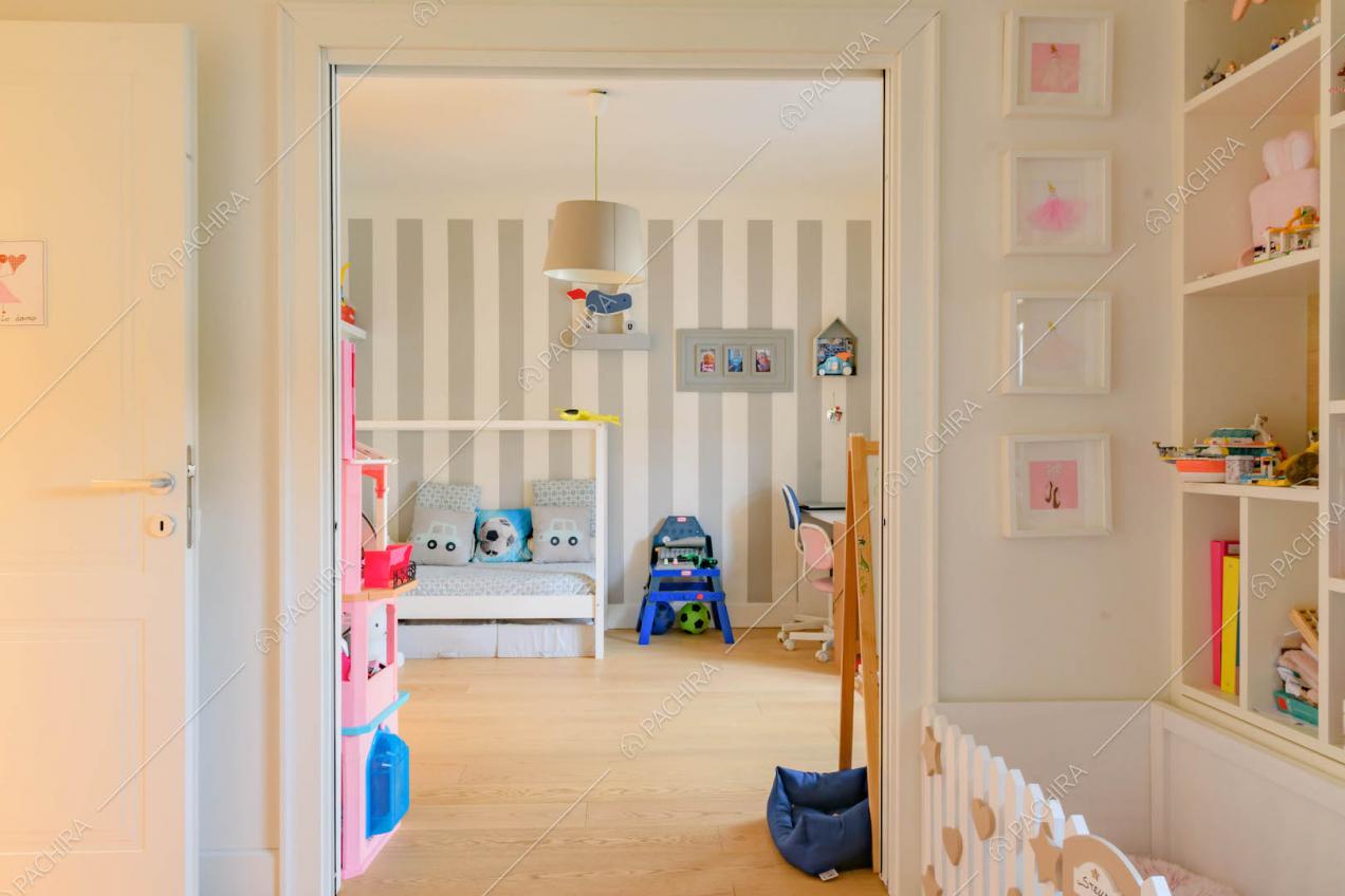Vista sulla camera da letto dei bambini con parete a strisce bianche e grigie