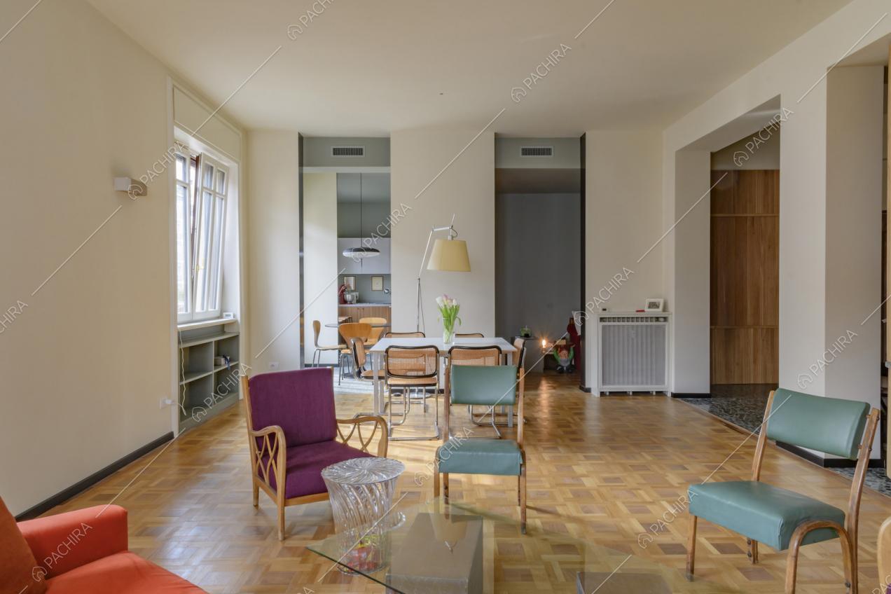 Salotto dalle pareti bianche con pavimento in parquet e tavolo da pranzo bianco