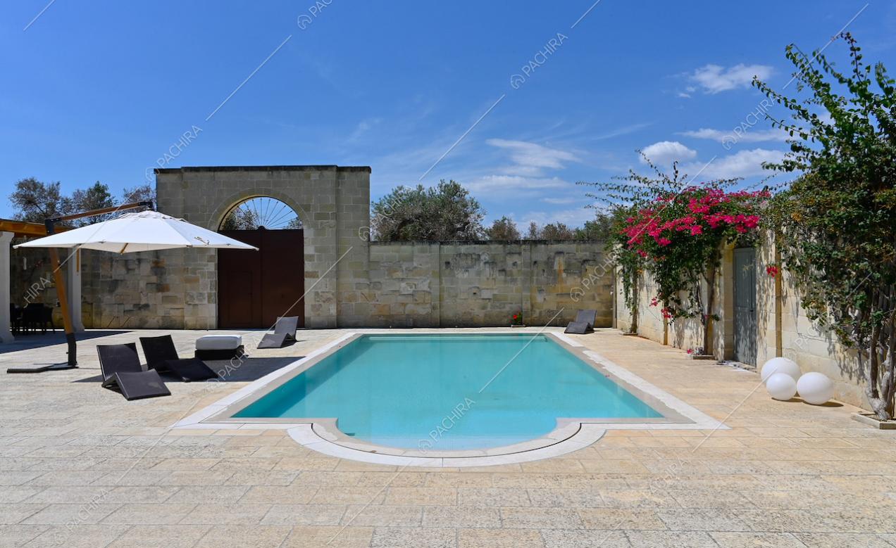 Nel cortile della villa circondata da mura in pietra, meravigliosa piscina con ombrellone e lettini