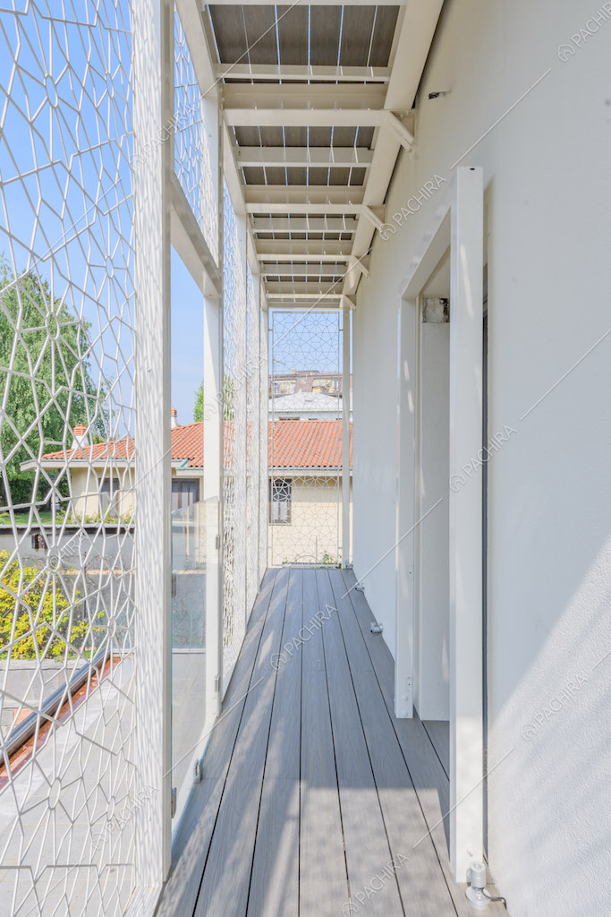 Balcone con parapetto geometrico bianco e pavimento in parquet da esterni