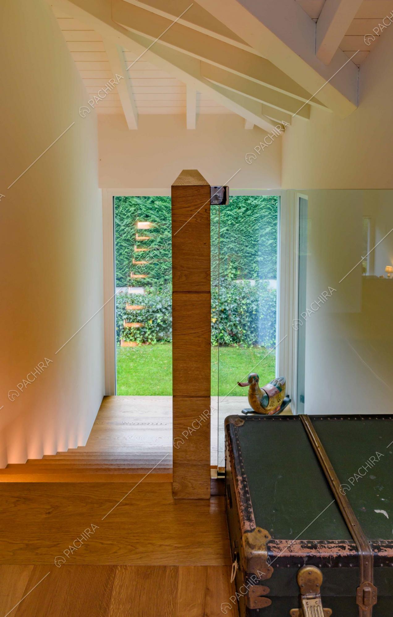 Dalle scale in legno con pianerottolo unico vista sul giardino tramite le ampie vetrate