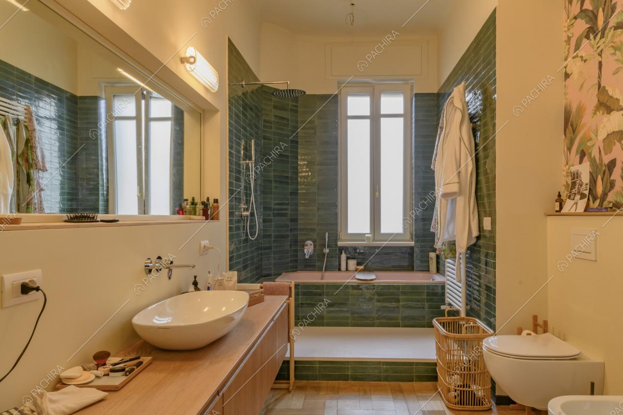 Bagno con pavimento in parquet, box doccia e vasca con piastrelle verdi