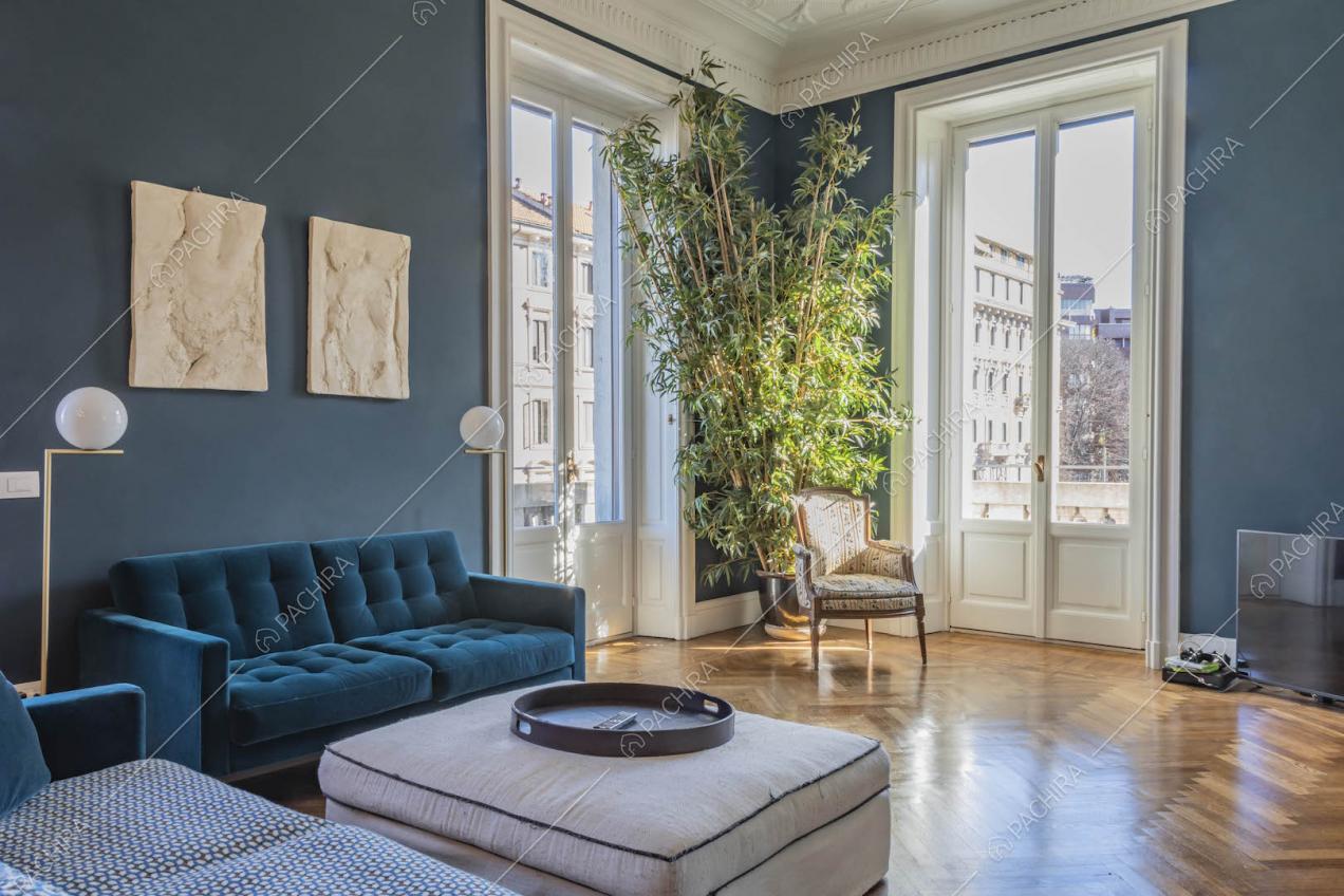 Divani blu nel salotto con pavimento in parquet, porte-finestre e boiserie sul soffitto