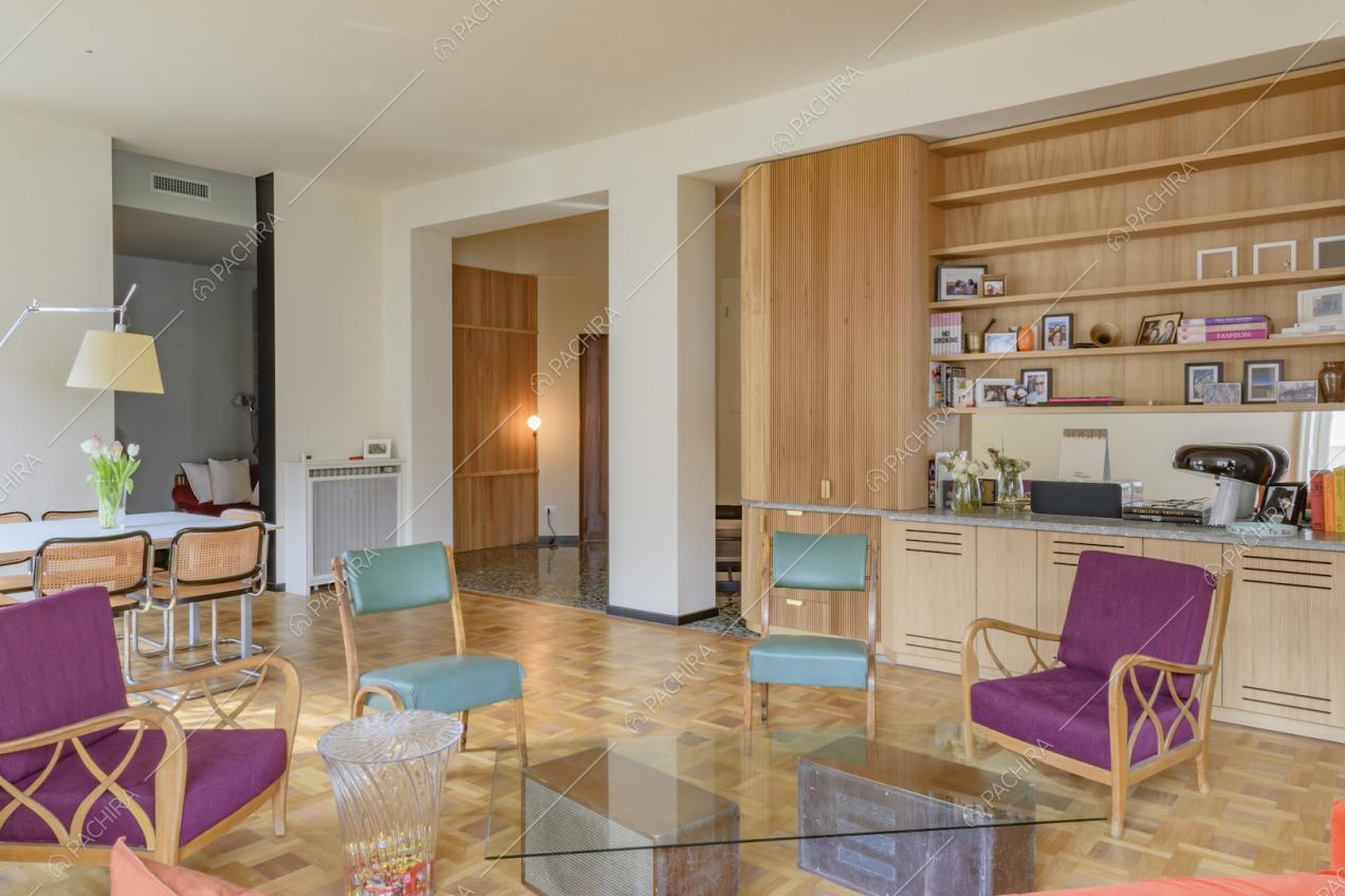 Tavolino del soggiorno con piano in vetro, pavimento in parquet e libreria a parete