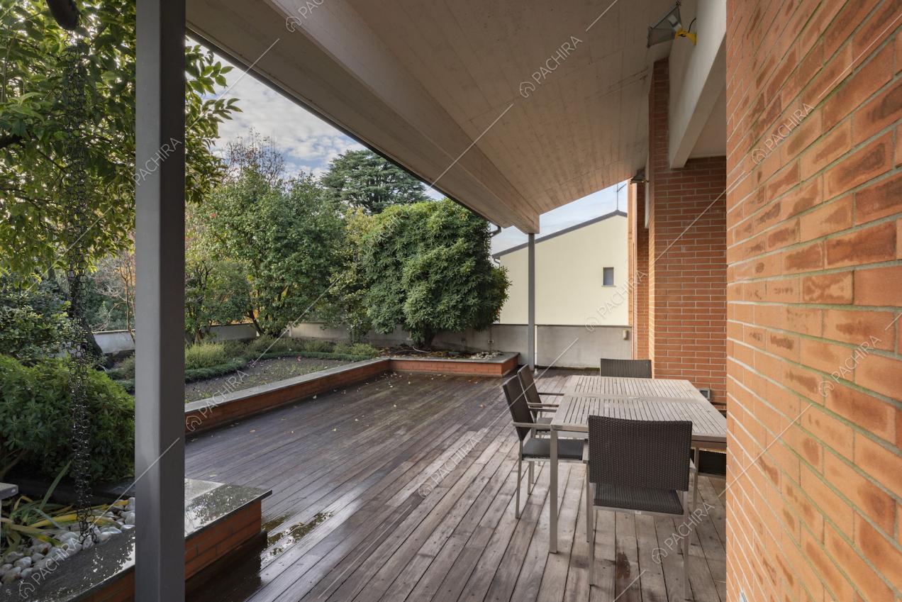 Veranda con tettoia, pavimento in legno e vista sul giardino