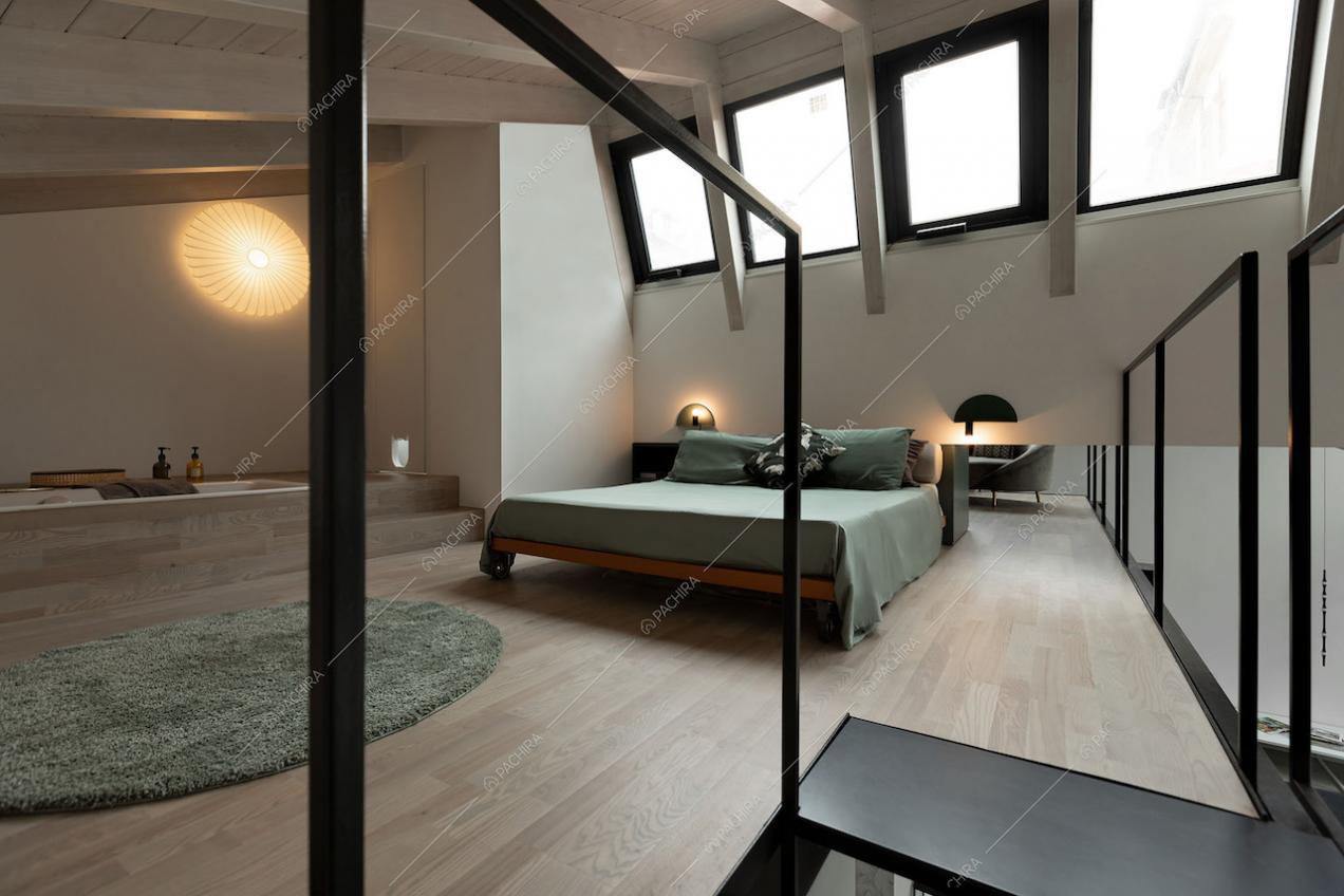 Ampia camera da letto matrimoniale con vasca a vista, lucernari e pavimento in parquet