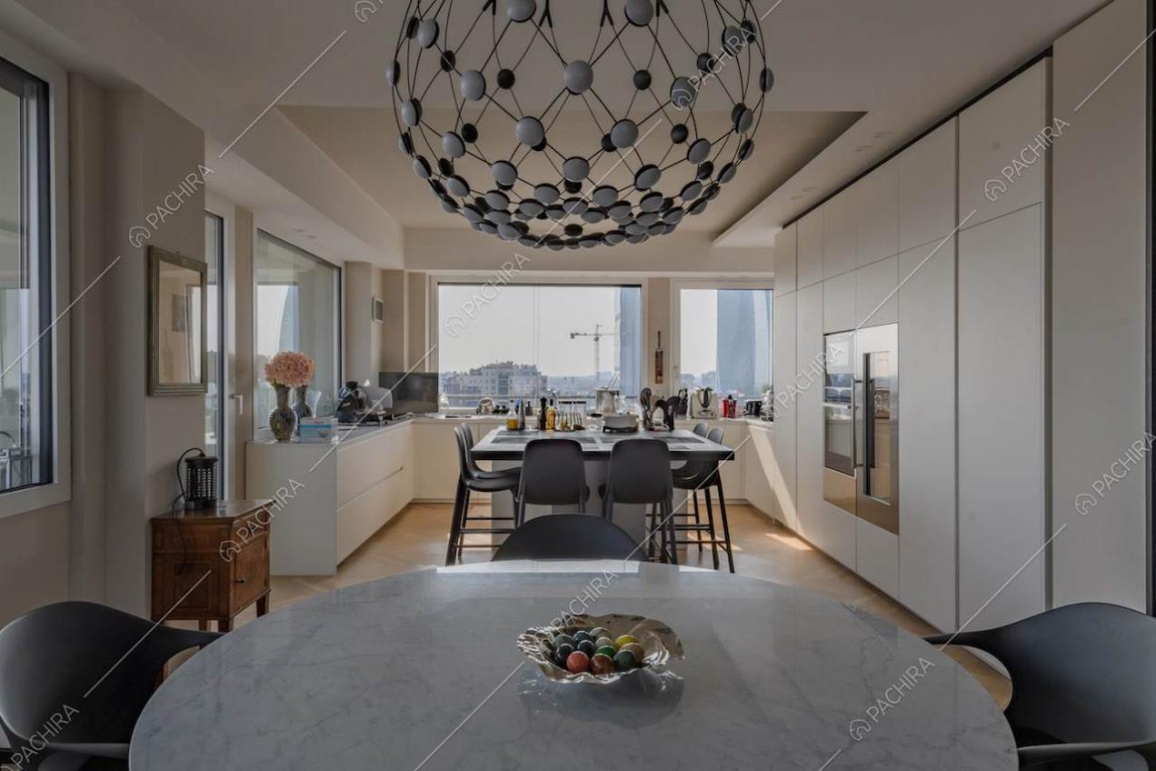 Dal tavolo da pranzo rotondo vista sulla cucina con isola e sugli armadi a muro