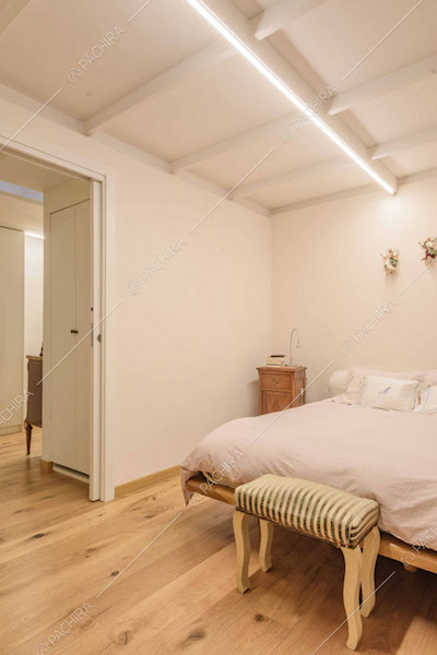 Camera da letto matrimoniale con pareti bianche e travi a vista sul soffitto