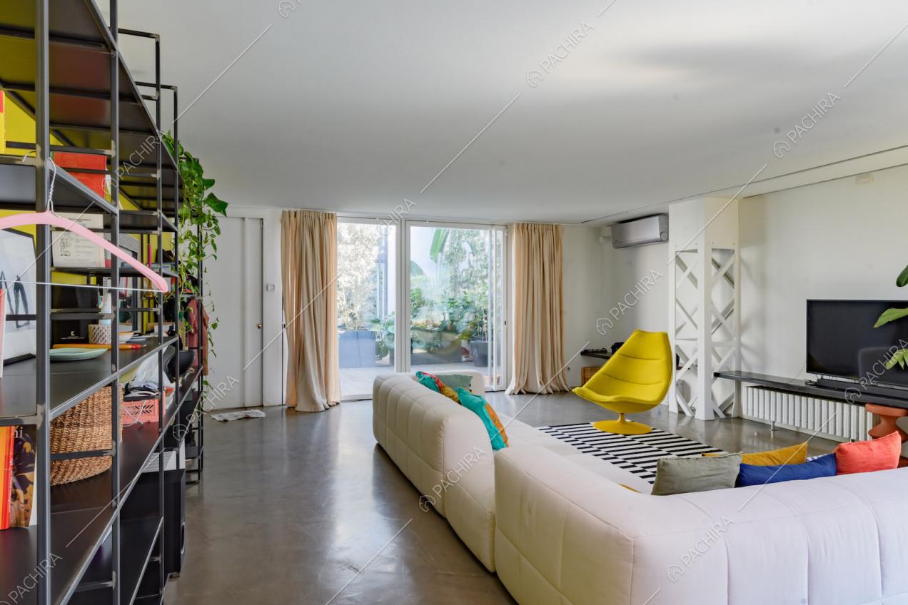 Divano angolare bianco nella luminosa zona living con porta-finestra e vista sulla terrazza