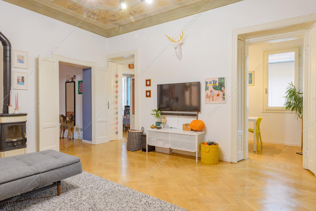 Pavimento in parquet a spina di pesce e divano angolare grigio nella sala