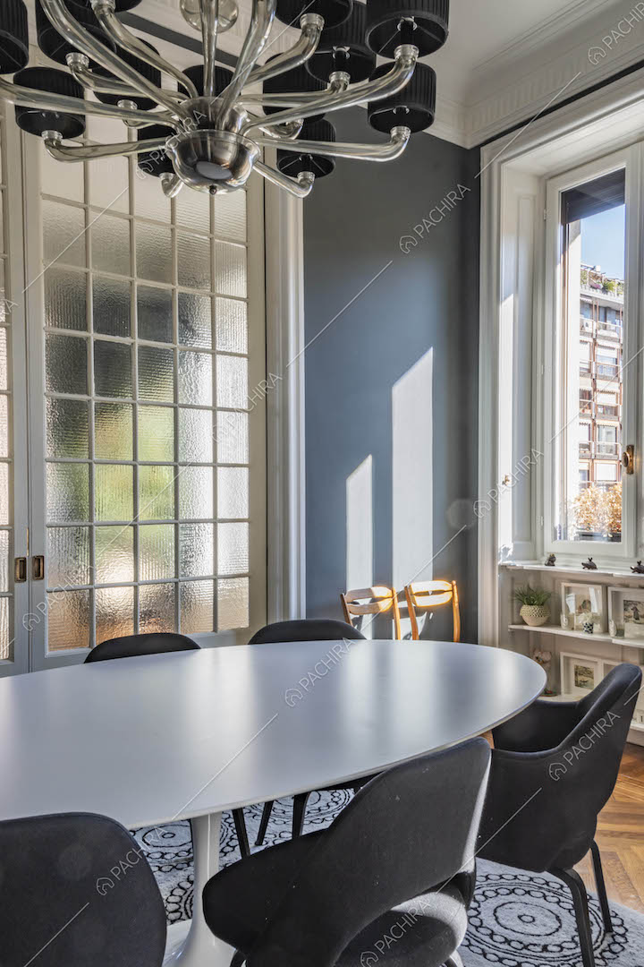 Tavolo da pranzo ovale nella sala con pareti blu e porta a vetri scorrevole