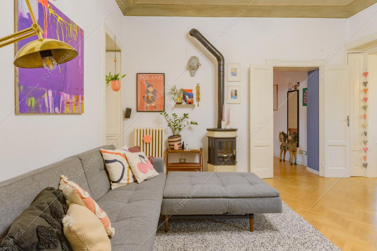Divano angolare grigio, stufa e soffitto affrescato nella luminosa zona living