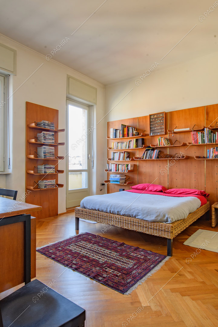 Letto matrimoniale della camera con pavimento in parquet e porte-finestre