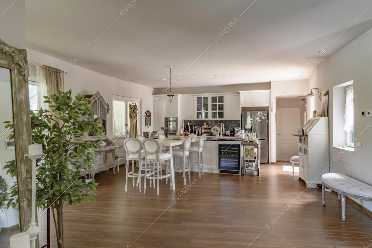 Cucina, dalle pareti bianche, a isola con lavandino, piano in marmo e bancone con sgabelli