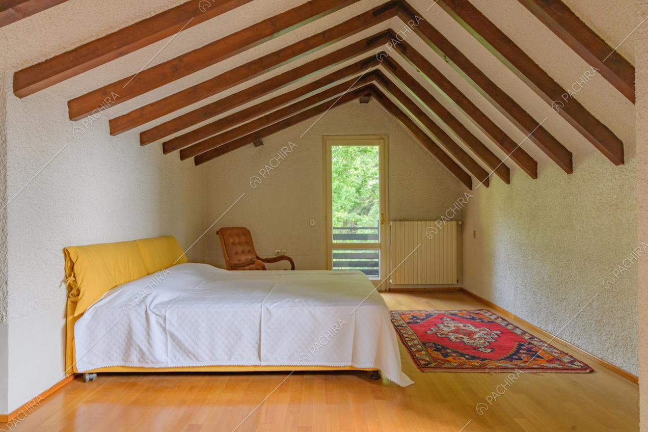 Camera da letto matrimoniale con pavimento in parquet e travi in legno sul soffitto
