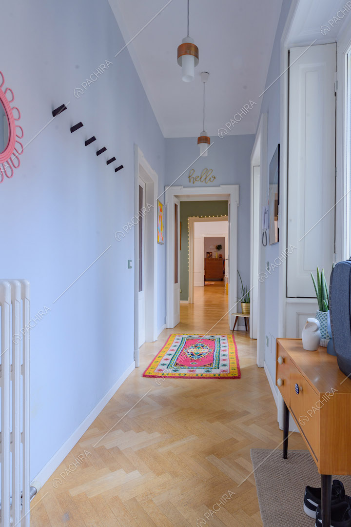 Lungo corridoio con pareti azzurre e pavimento in parquet a spina di pesce