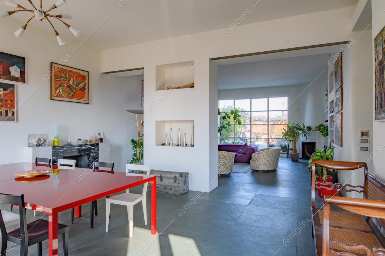 Tavolo da pranzo rosso nella luminosa zona living con pareti bianche e vetrata in stile industriale