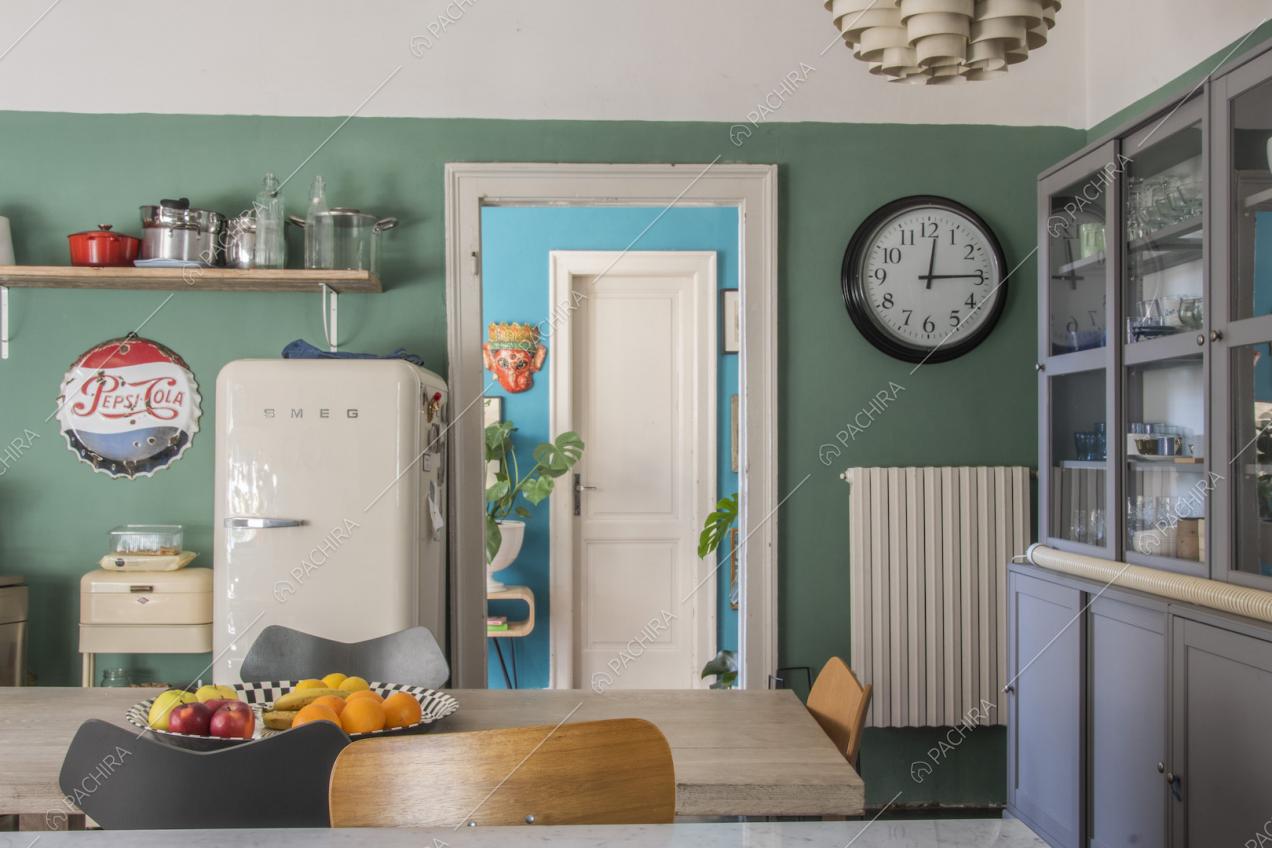 Orologio da muro e mensola di legno sulla parete verde della cucina