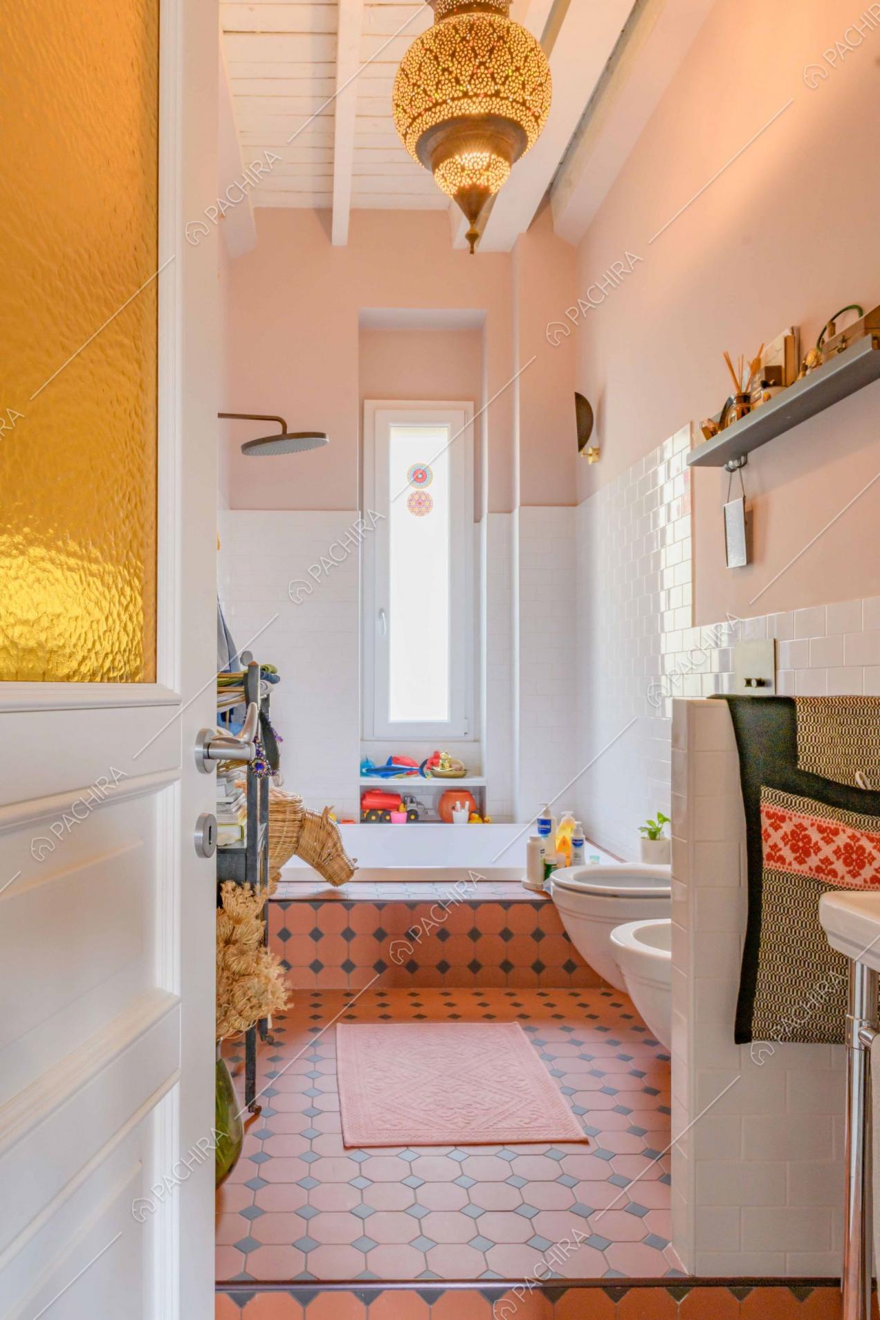 Bagno con pavimento in piastrelle rosse e nere, pareti rosa e in piastrelle bianche