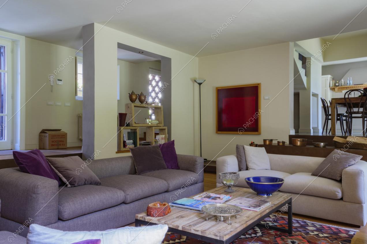 Divani viola nel salotto con pavimento in parquet e vista su tavolo da pranzo e cucina