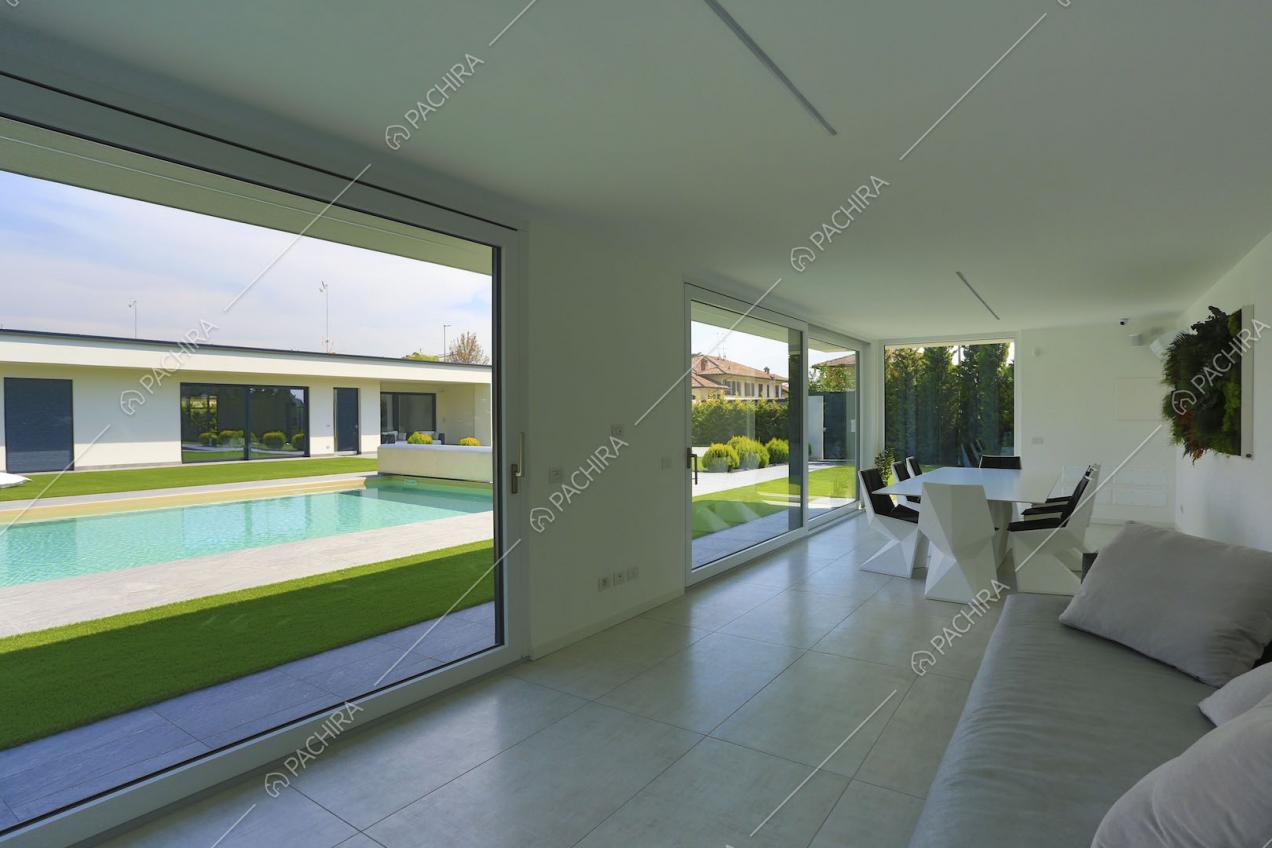 Dal divano vista sulla piscina attraverso le ampie vetrate scorrevoli