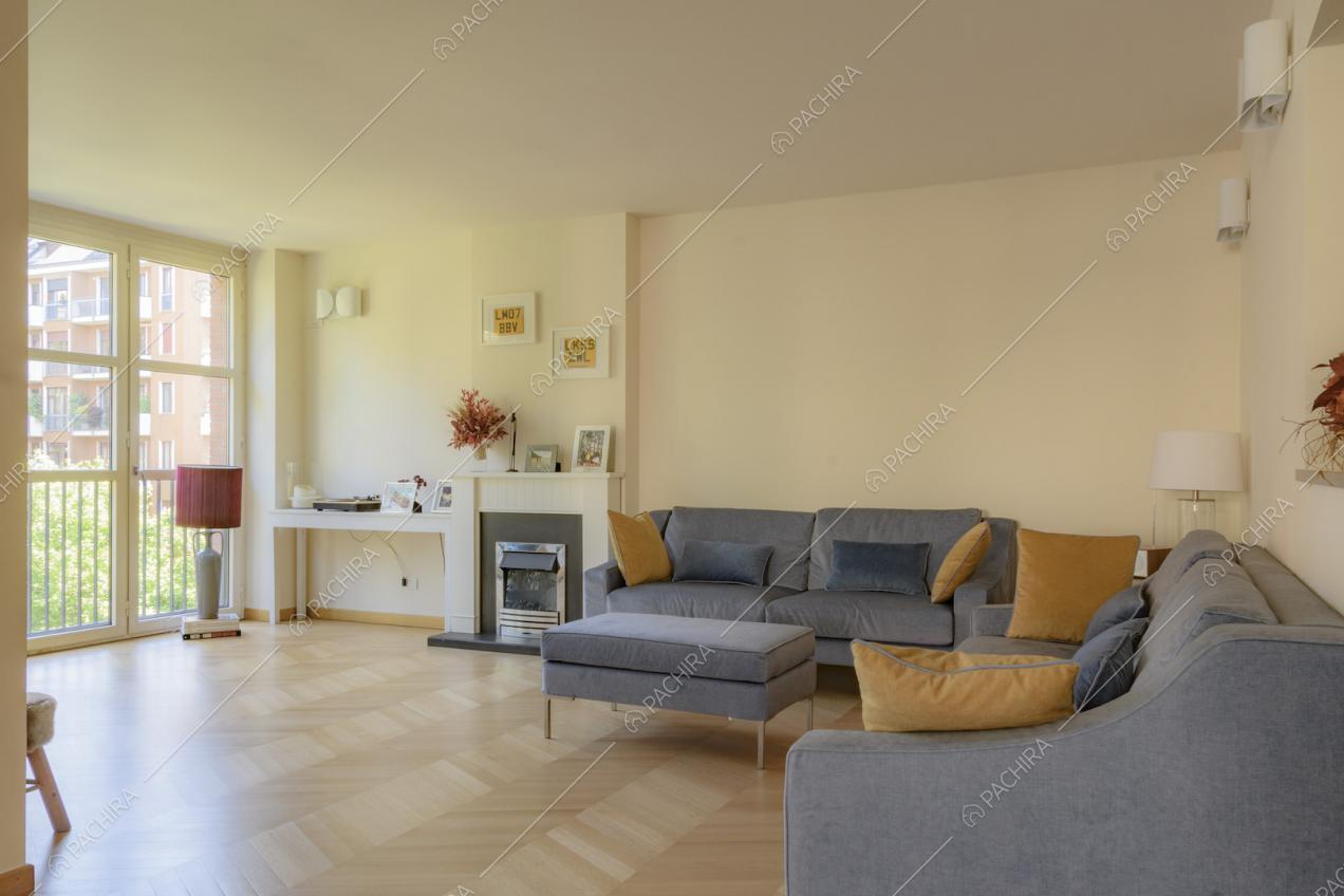 Luminoso soggiorno con pavimento in parquet, divano e camino