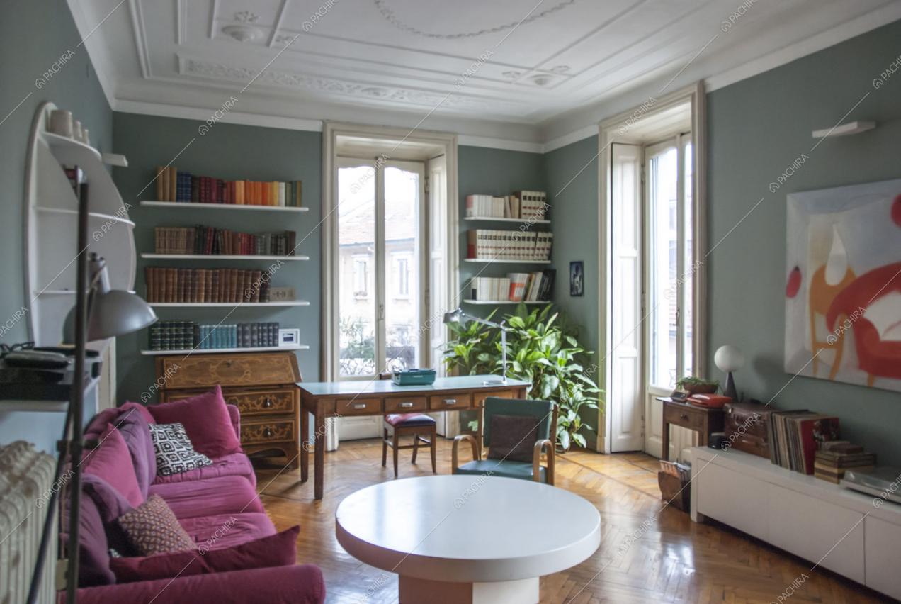 Vista sulla zona living con due porte finestre e soffitto in boiserie