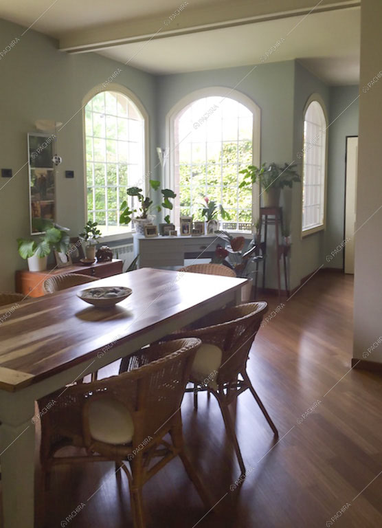 Sala da pranzo con tavolo su pavimento in parquet e vetrate
