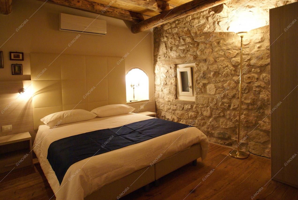 Camera da letto con pavimenti in parquet e pareti in sasso