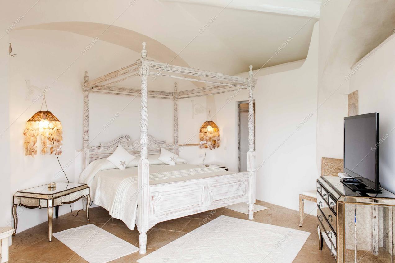 Camera da letto con baldacchino, cassettiera a specchio e televisione