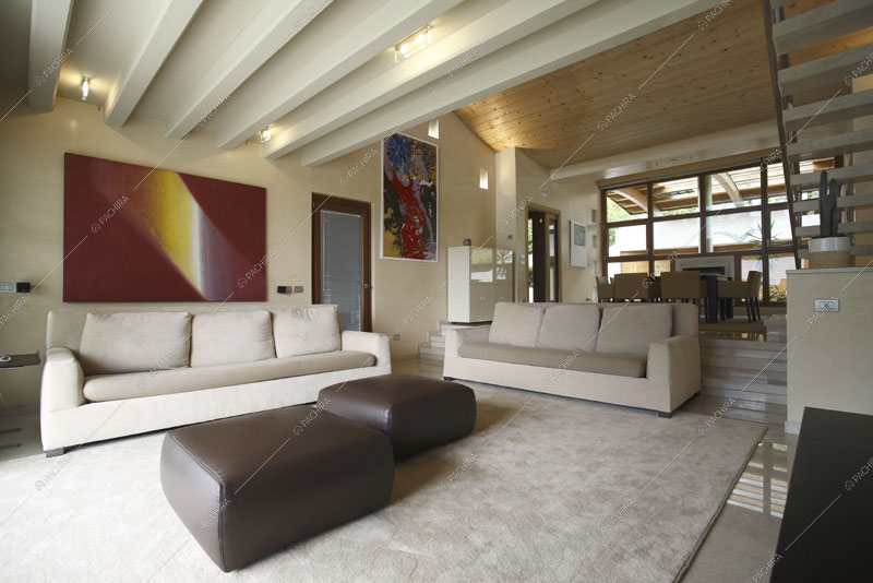Soffitto con travi a vista e scorcio sul tavolo da pranzo dalla zona living