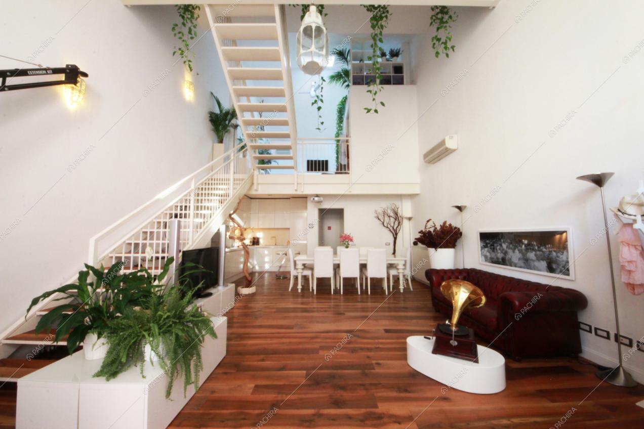 Zona living con parquet a listoni e scale bianche