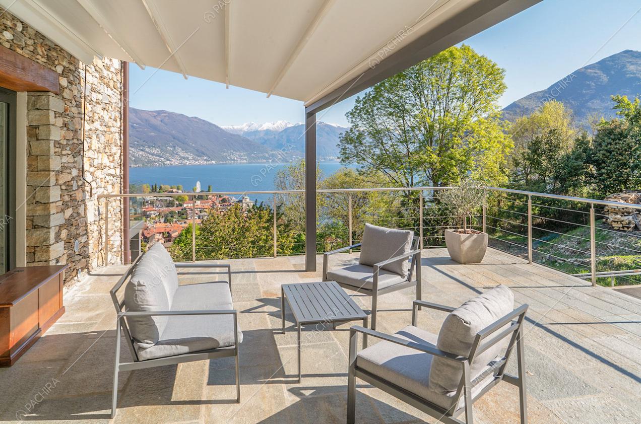 Sulla terrazza dal pavimento in pietra, veranda con salotto da esterni e vista sul lago