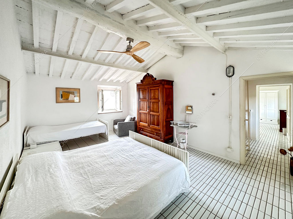 Camera da letto matrimoniale con pavimento in piastrelle bianche e vista sul corridoio