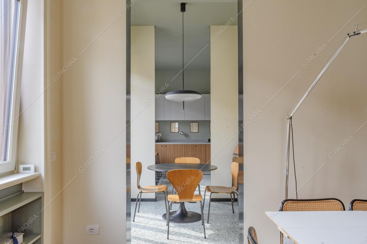 Vista sul tavolo da pranzo nero con sedie di legno di design e sulla cucina a muro