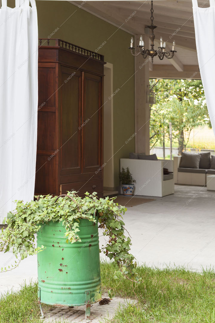 Dal giardino vista sulla veranda con divani da esterno e armadio in legno