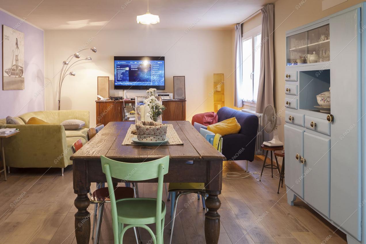Sala con tavolo da pranzo in legno, credenza azzurro pastello e divani