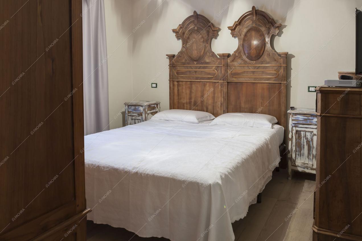 Camera da letto matrimoniale con testata in legno intagliato