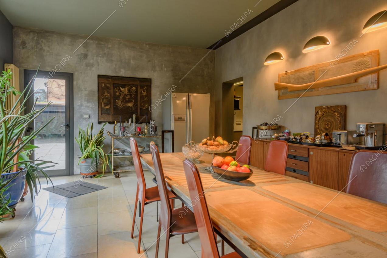 Luminosa sala da pranzo con grande tavolo, sedie rosse di design e porta-finestra