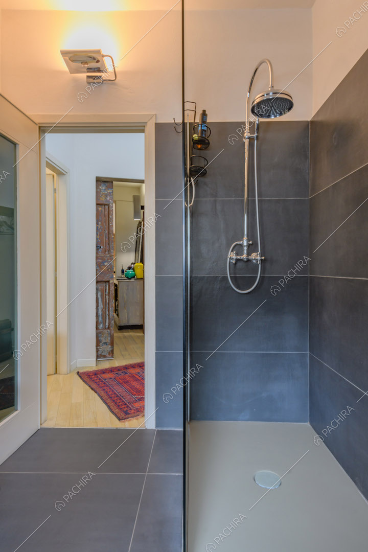 Box doccia nel bagno con pavimento e pareti in piastrelle nere