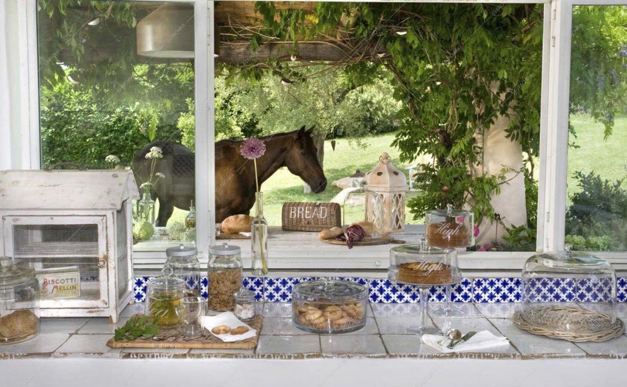 Piano di lavoro della cucina in piastrelle bianche e ampia finestra con vista sul giardino