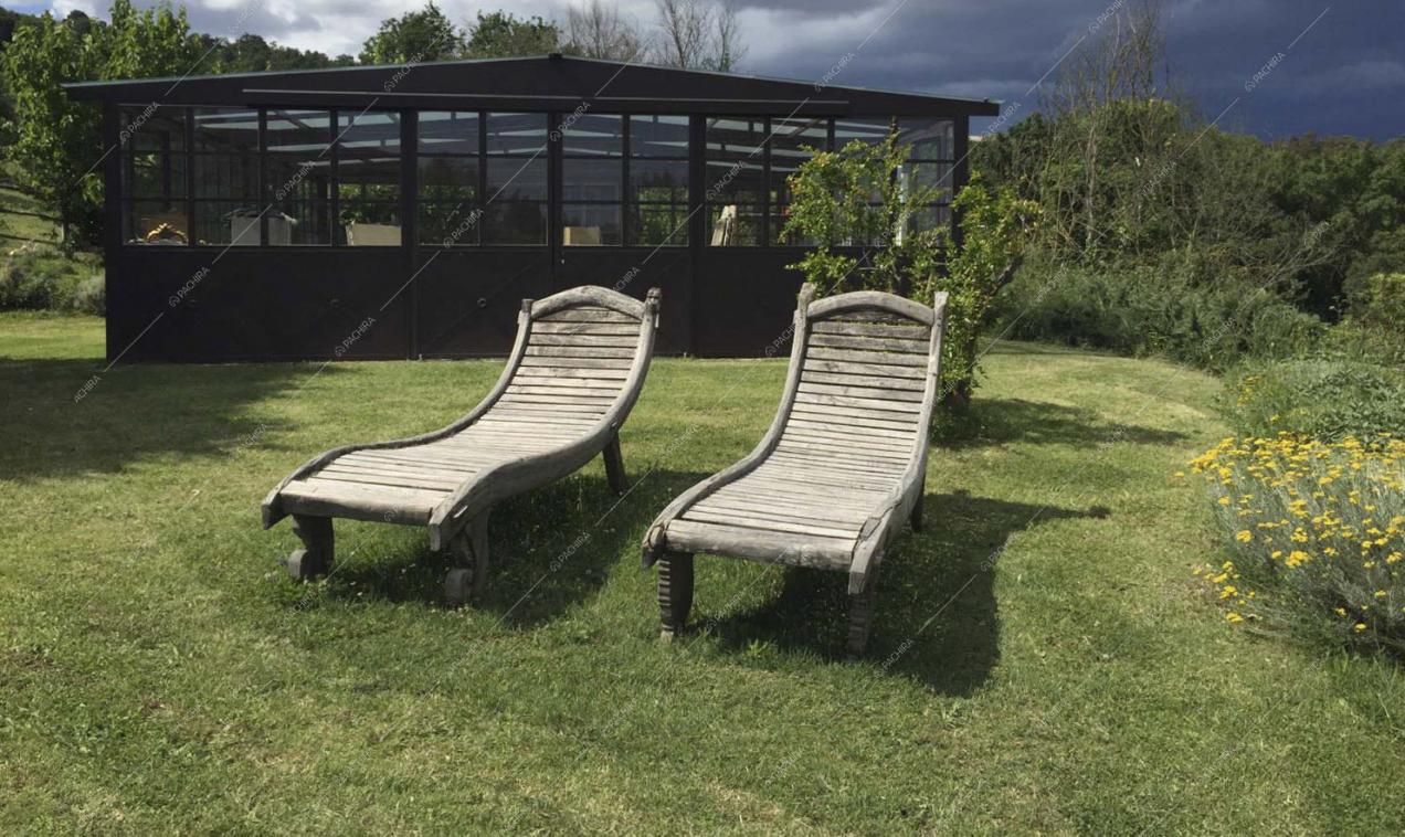 Lettini in legno nel parco davanti alla serra in stile industriale